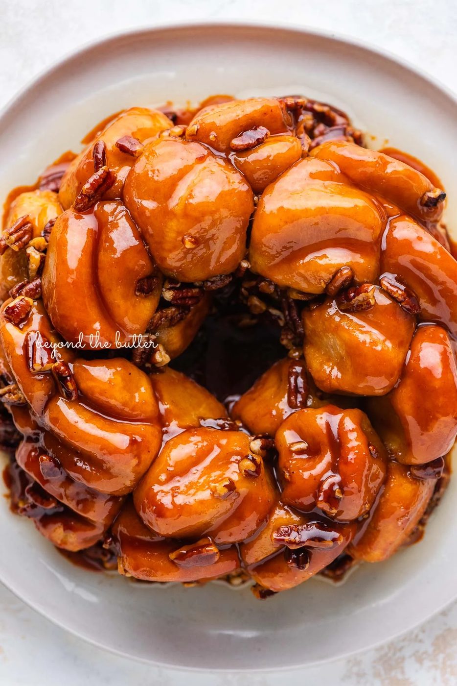 Overhead view of butterscotch bundt rolls on white dessert plate and white background | © Sovuh