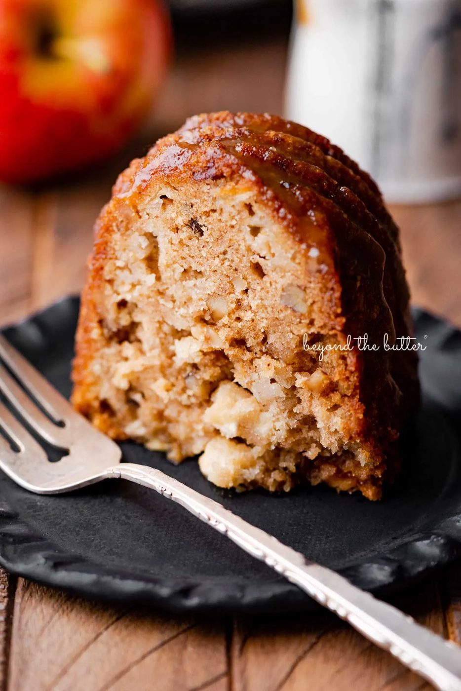 Slice of house-made apple bundt cake on dark wood background | © Sovuh