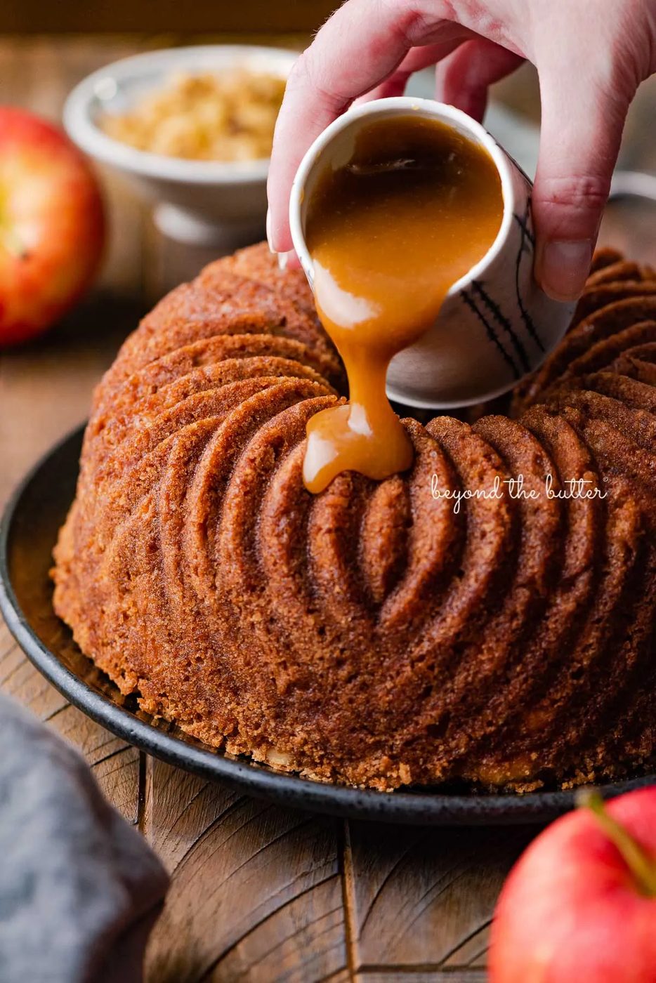 Pouring brown sugar glaze over top of warm apple bundt cake | © Sovuh