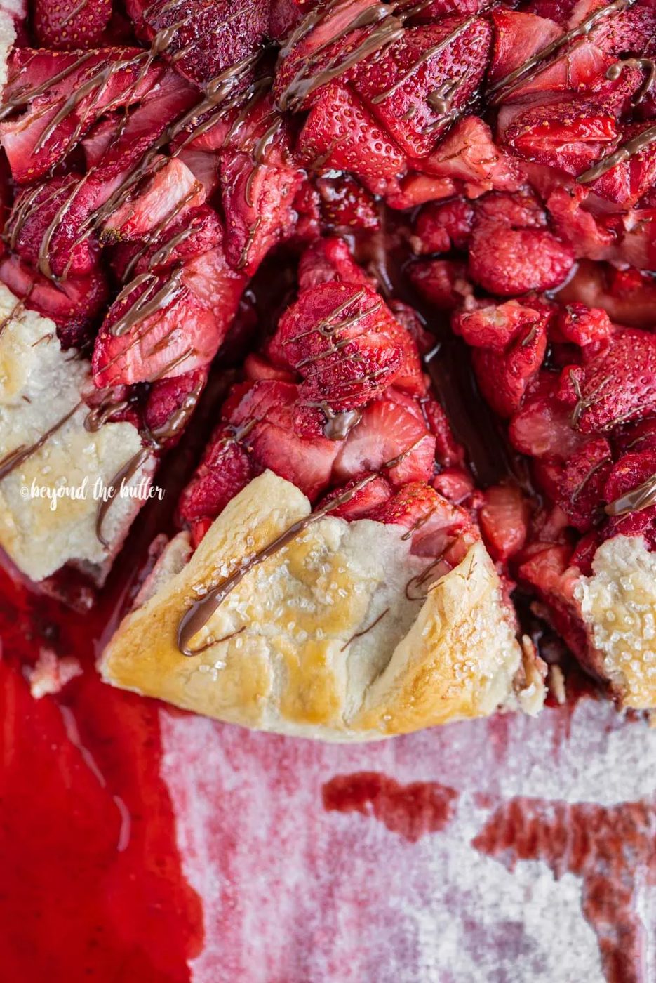Overhead image of a slice of Berry Nutella Galette on a baking sheet with Nutella drizzled over the top | All Images © Sovuh
