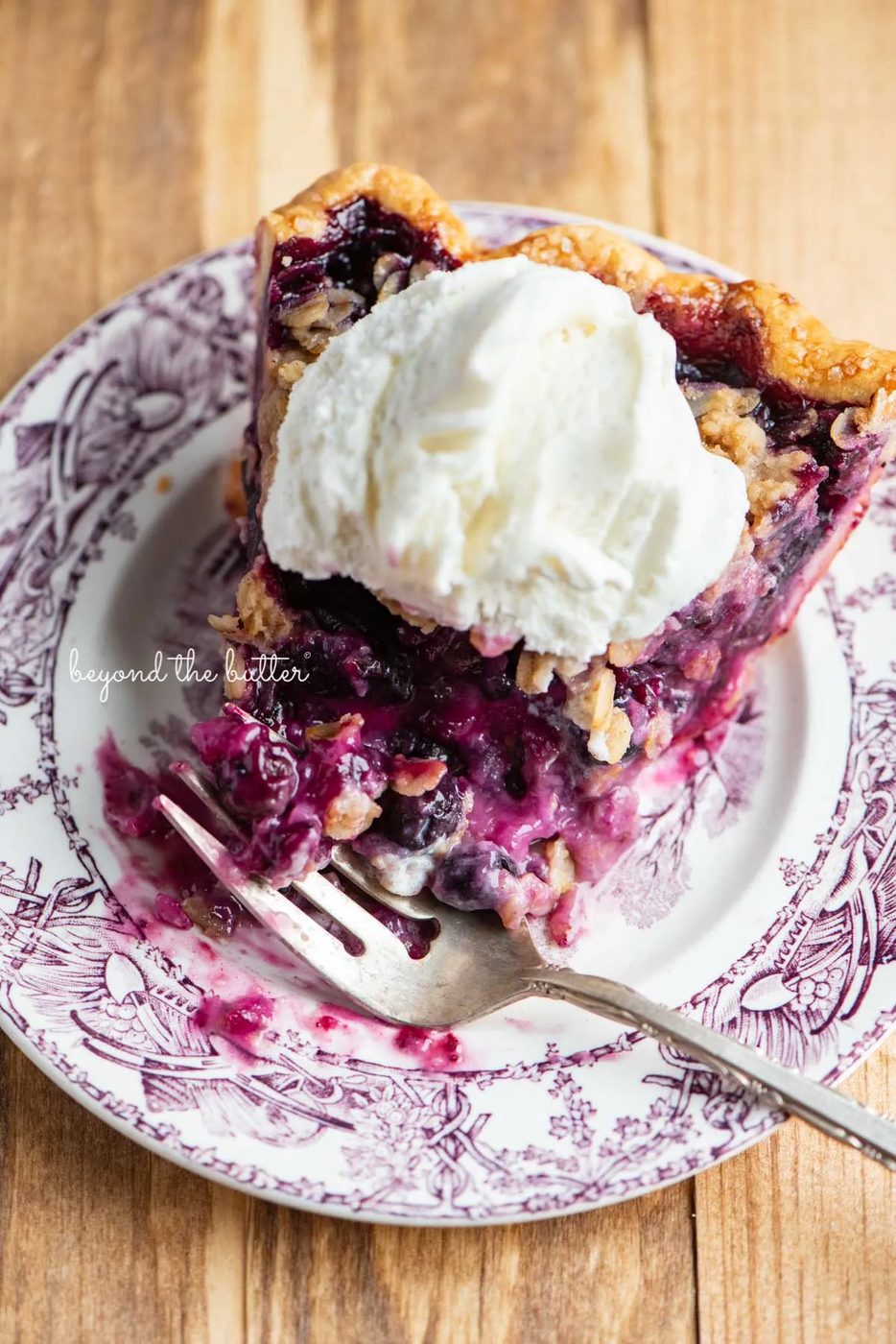 Half eaten slice of blueberry crumble pie with scoop of vanilla bean ice cream on top | © Sovuh