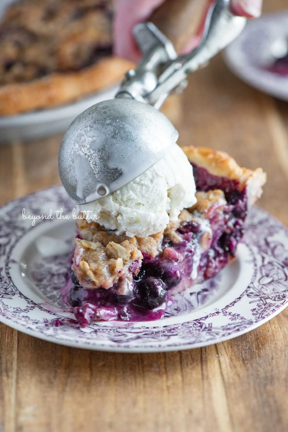 Slice of blueberry crumble pie with scoop of vanilla bean ice cream on top | © Sovuh