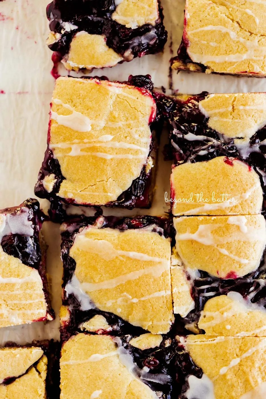 Sliced blueberry swirl coffee cake squares on a white parchment paper background.