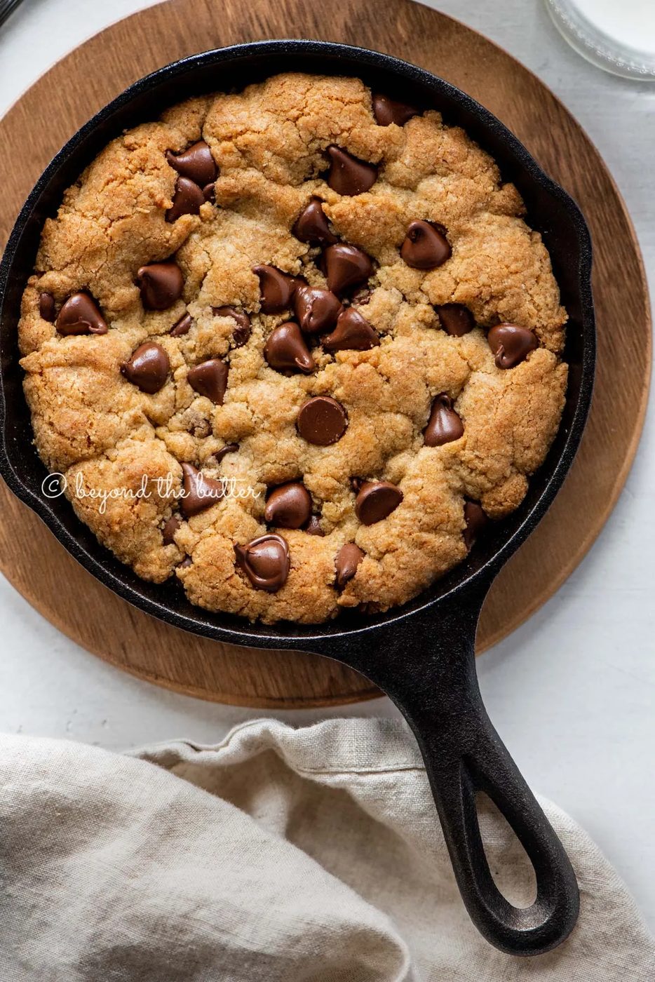 Just baked chocolate chip skillet cookies on light gray background with cloth napkin | All Images © Sovuh