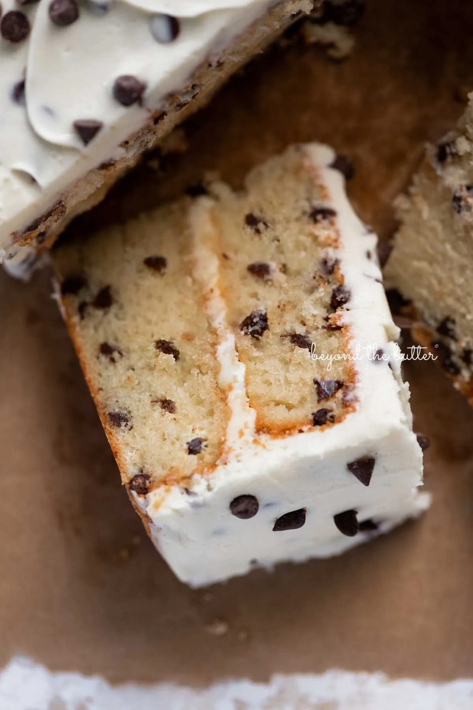 Slice of 2 layer chocolate chip cake on it's side on a brown paper background | © Sovuh
