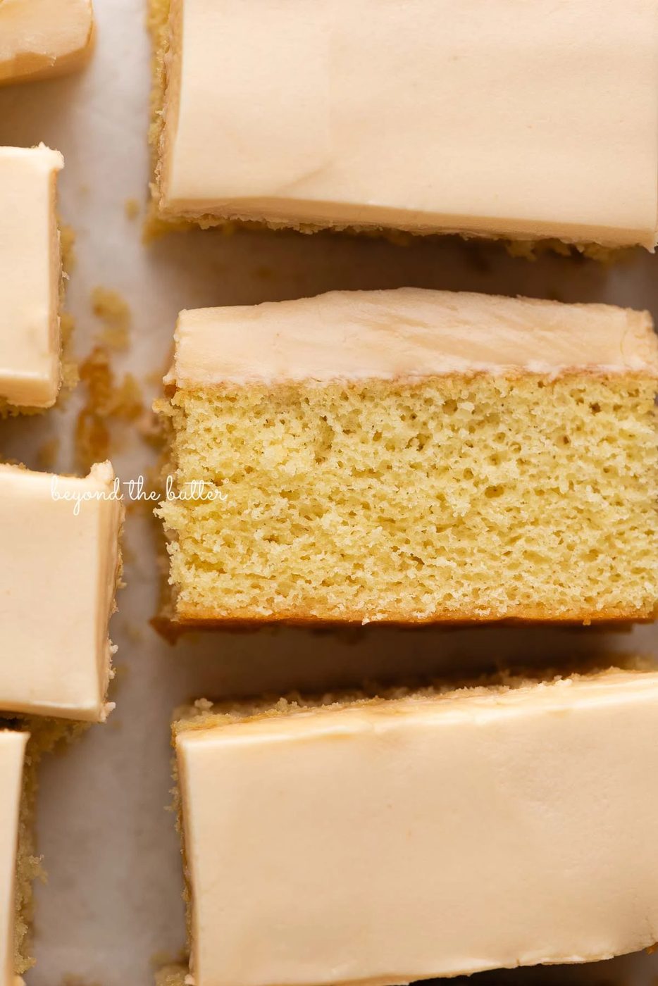Rectangular slices of butterscotch krimpets placed on a parchment paper lined background with center slice on its slide.