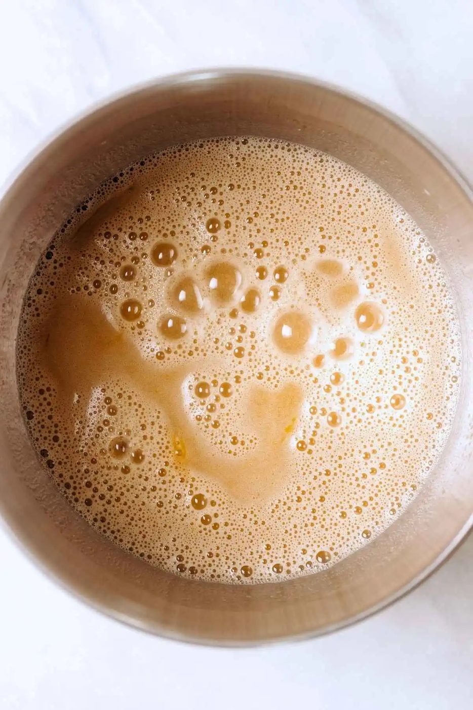 Espresso powder and boiling water added to cake batter wet ingredients in a stainless steel mixing bowl.