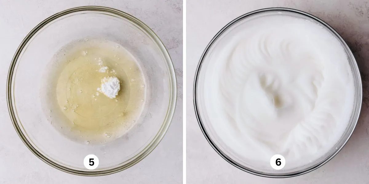 Mixing egg whites and cream of tartar into stiff glossy peaks in a large glass mixing bowl on a white marbled background.