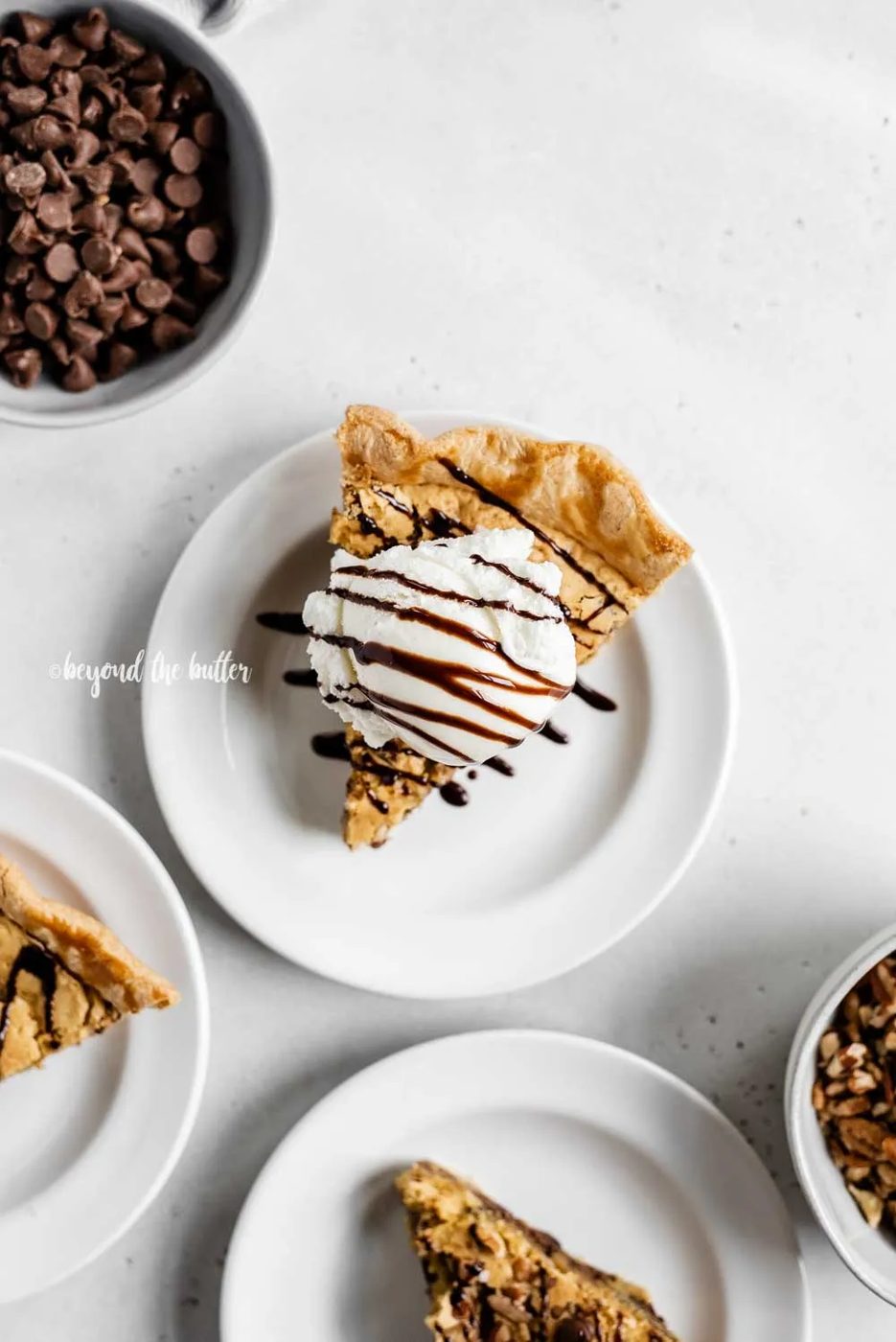 Overhead image of 3 slices of chocolate chip pie on dessert plates with one having a scoop of vanilla ice cream on top | All Images © Sovuh
