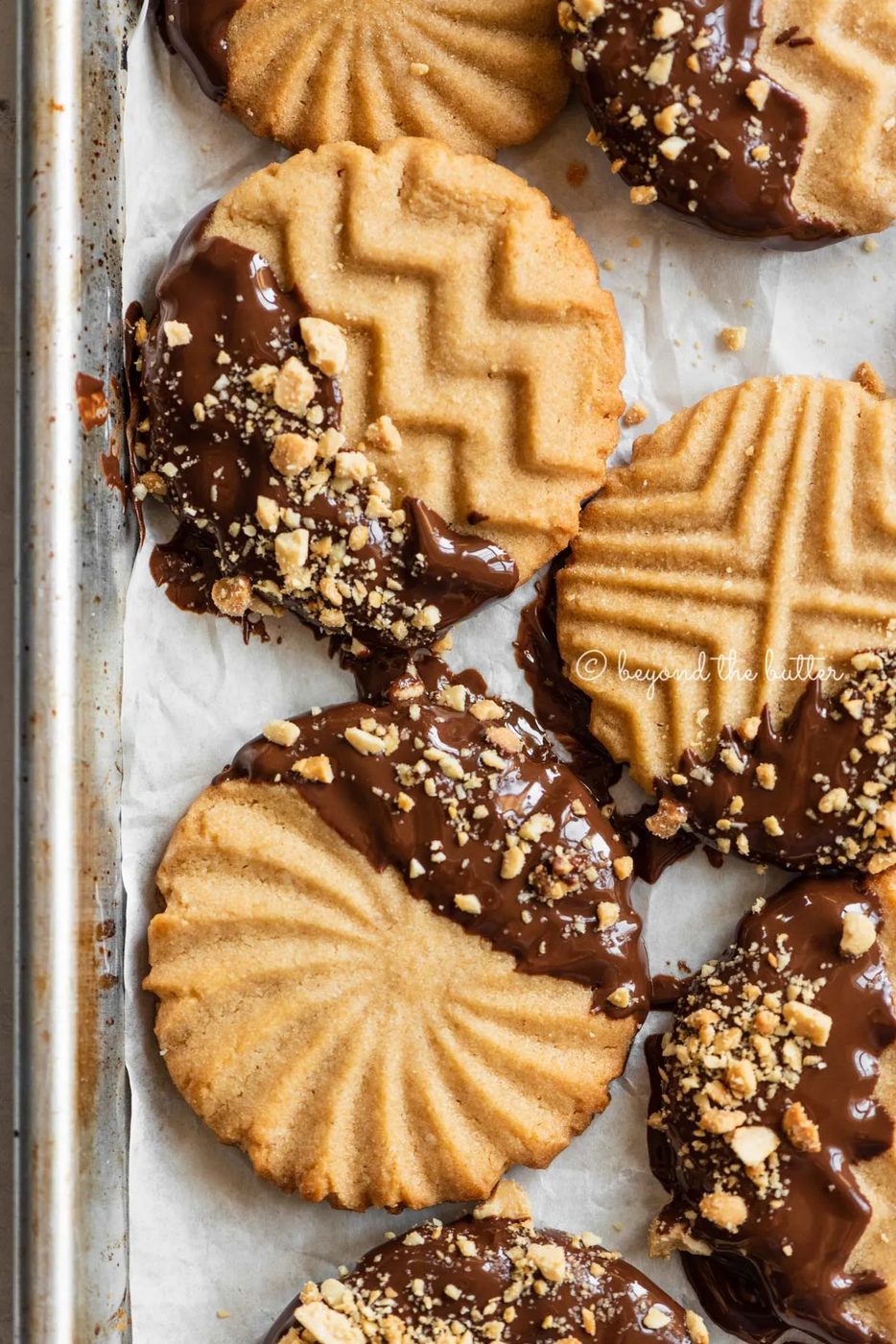 Baking sheet with randomly placed chocolate dipped peanut butter cookies | All Images © Sovuh