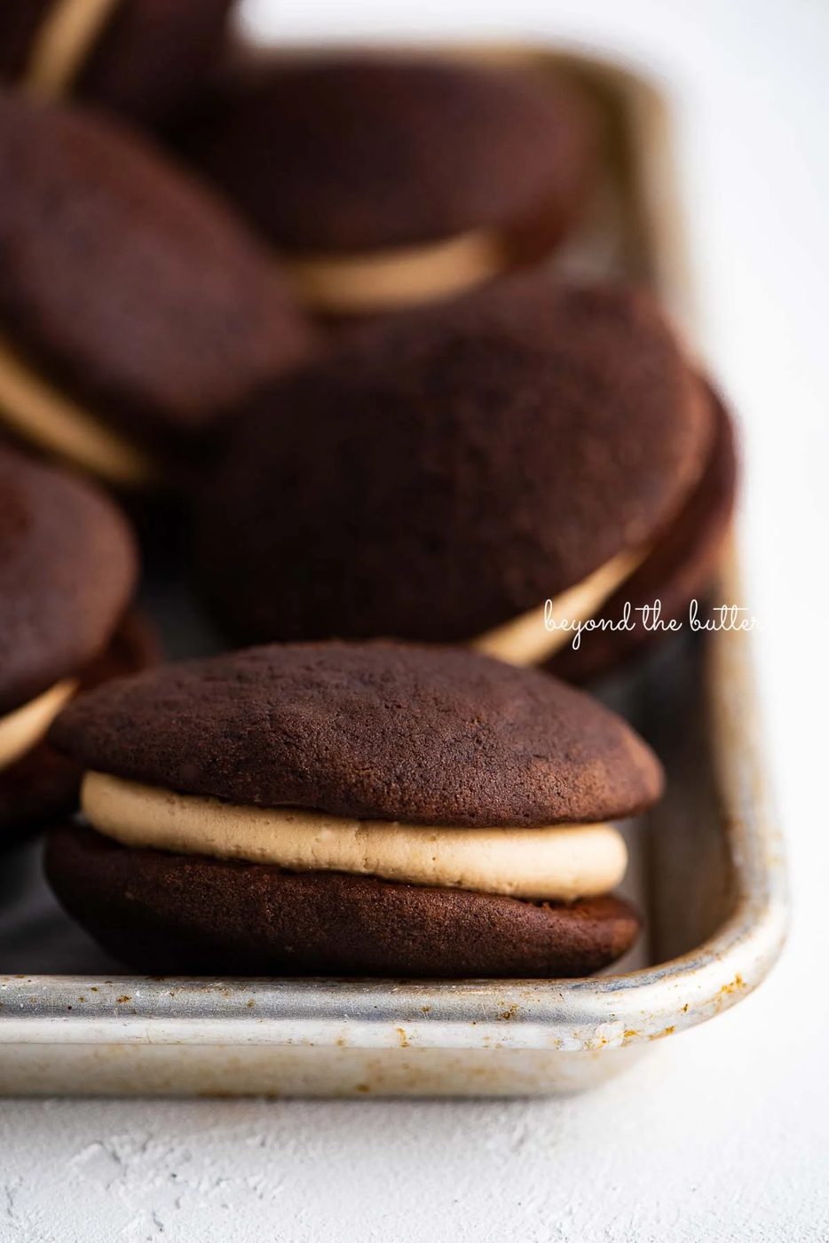 Chocolate peanut butter whoopie pies on a parchment lined baking pan | © Sovuh