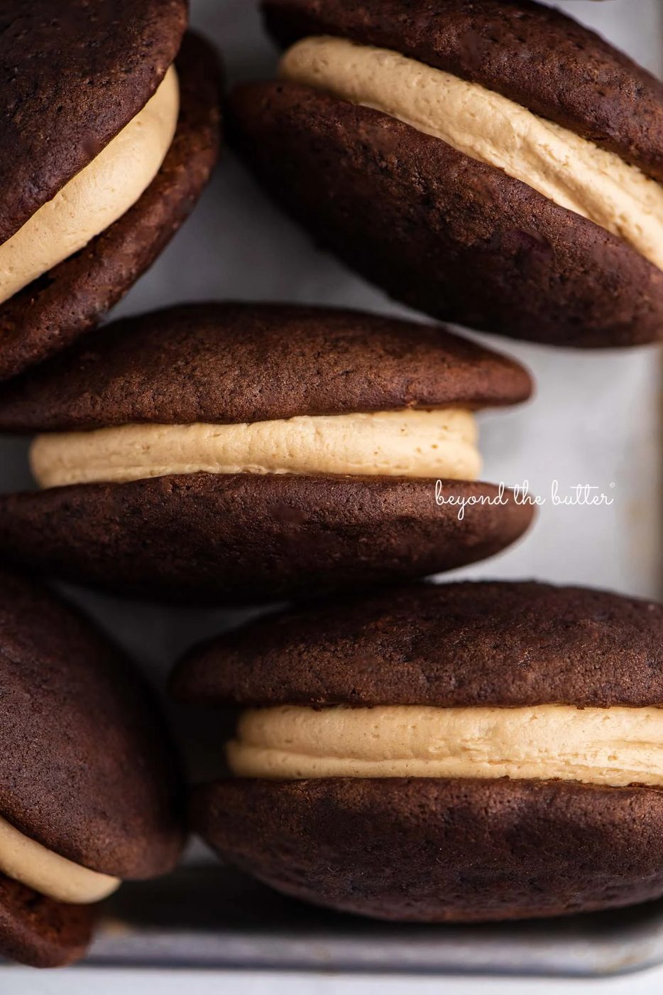 Chocolate peanut butter whoopie pies on a parchment lined baking pan | © Sovuh