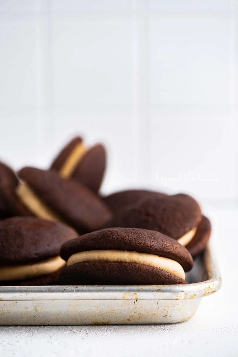 Chocolate peanut butter whoopie pies on a parchment lined baking pan | © Sovuh