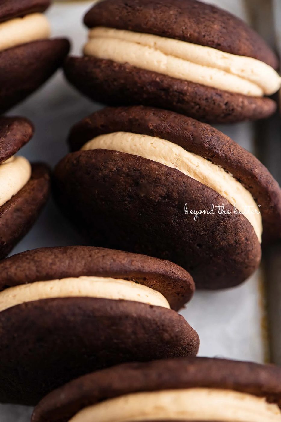 Chocolate peanut butter whoopie pies on a parchment lined baking pan | © Sovuh