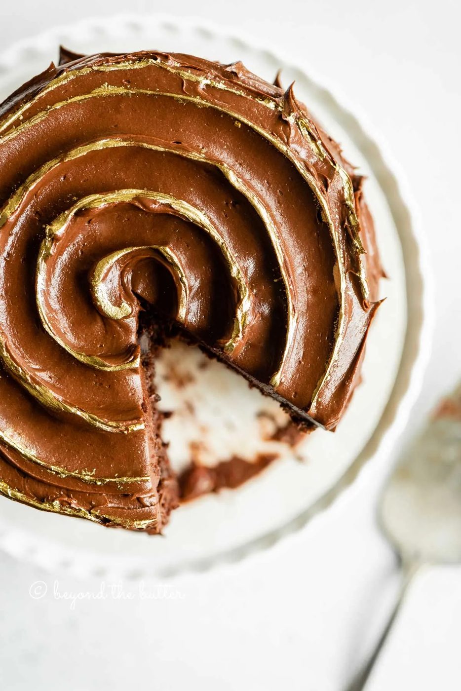 Overhead image of chocolate zucchini cake with chocolate chip with a slice removed | All Images © Sovuh