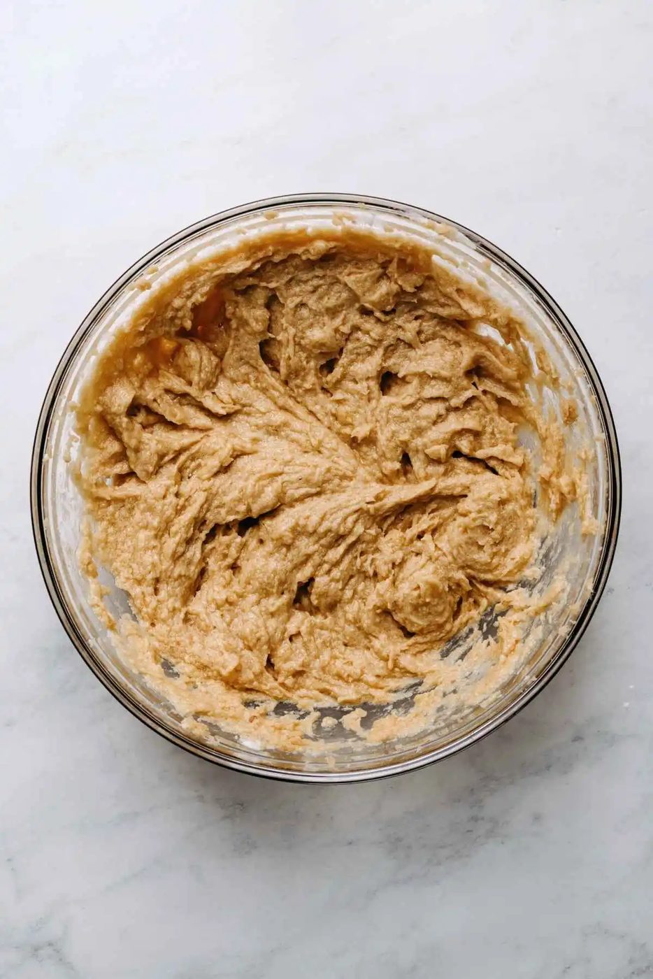 Eggs and vanilla extract blended into butter and sugar mixture in a large glass mixing bowl.
