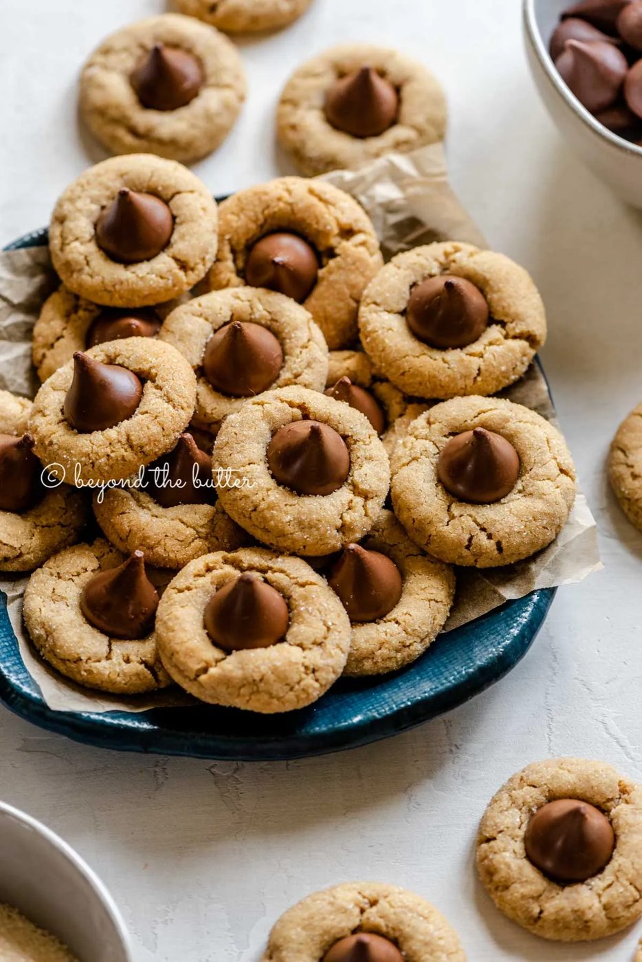 Angled image of familiar peanut butter blossoms on a parchment lined blue dessert platter | All Images © Sovuh