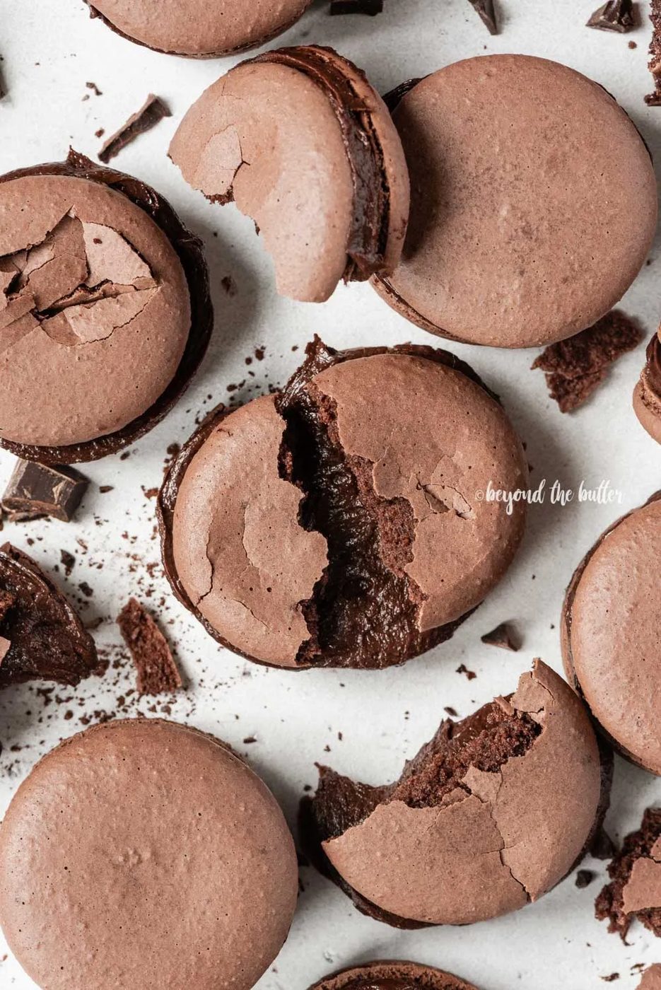 Scattered dark chocolate macarons with some broken or pulled apart | All Images © Sovuh