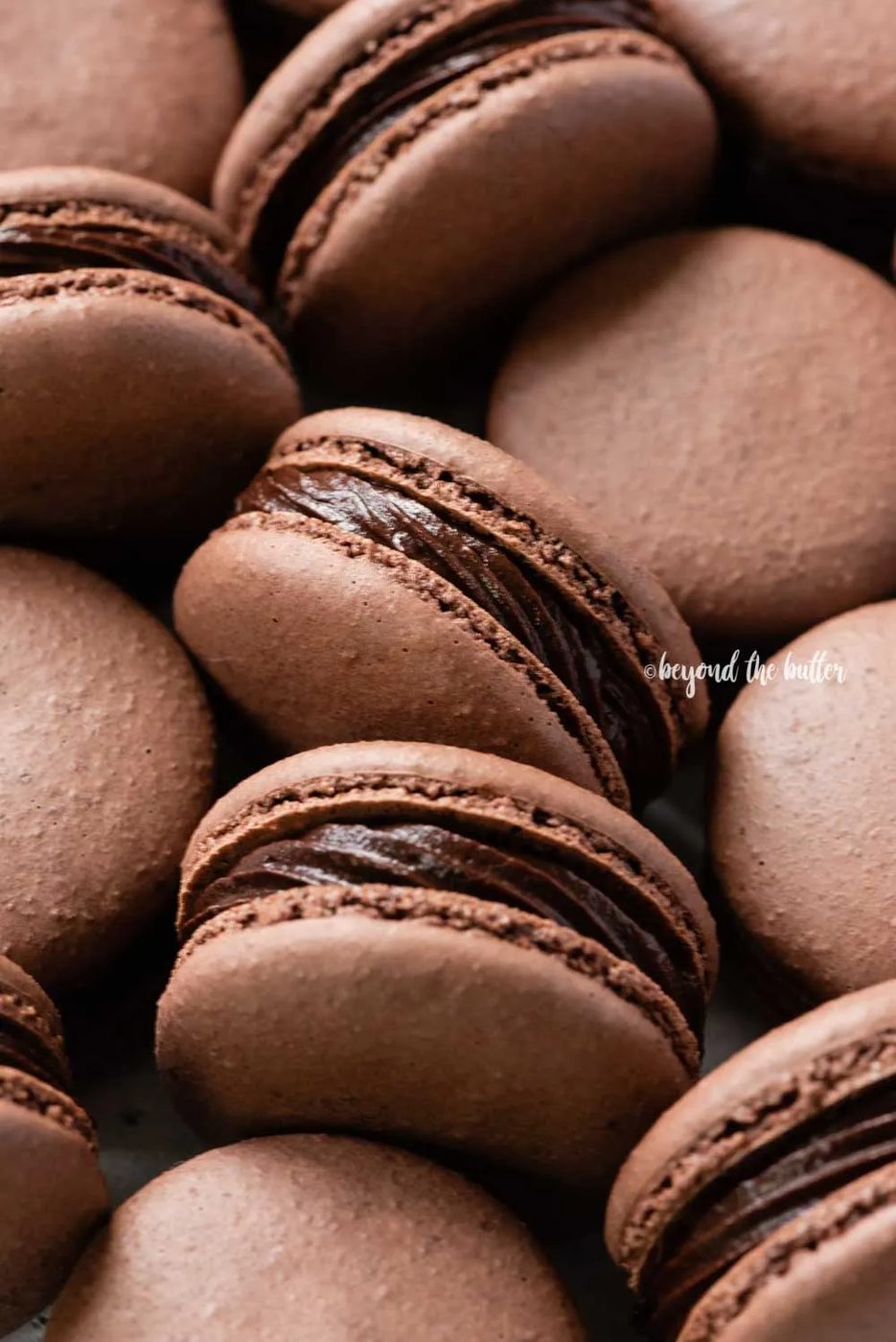 Angled image of randomly placed dark chocolate macarons | All Images © Sovuh