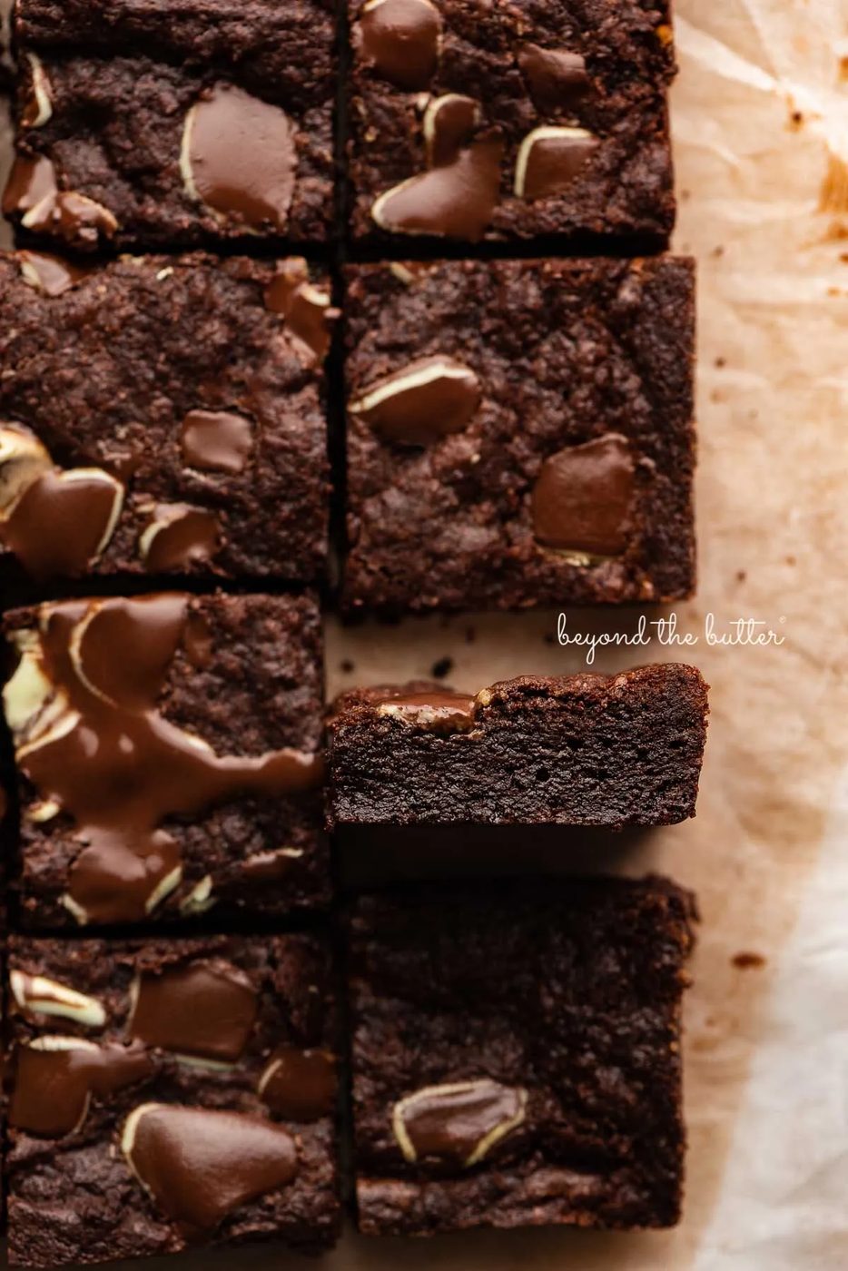 Double chocolate mint brownies on brown parchment paper background with the center brownie on its side | © Sovuh