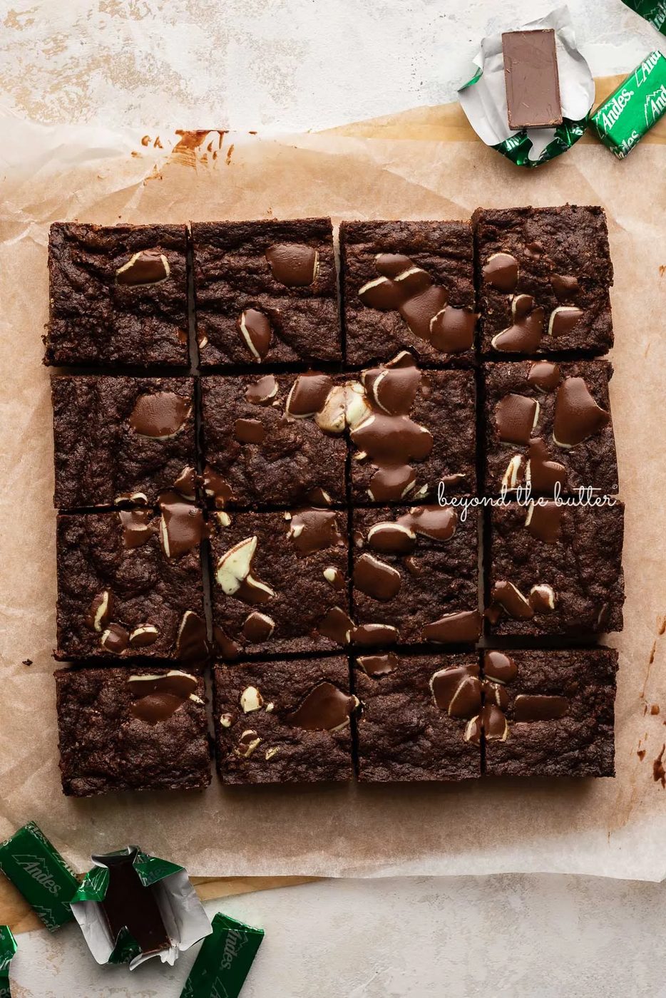 Just cut double chocolate mint brownies on brown and white sheets of crumbled parchment paper with andes mints around them | © Sovuh