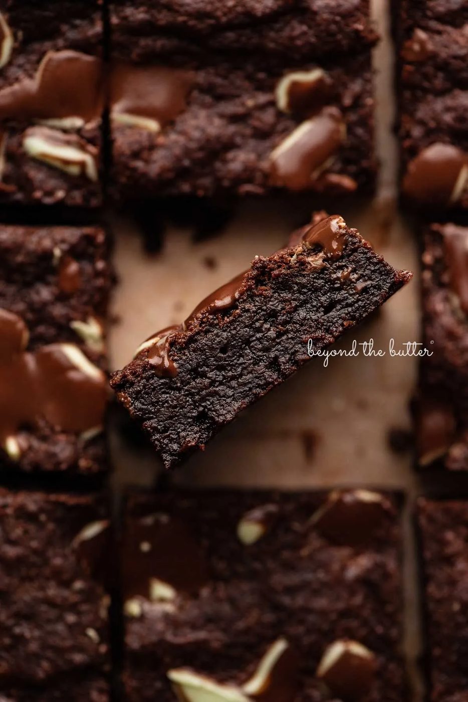 Double chocolate mint brownies on brown parchment paper background with the center brownie on its side | © Sovuh