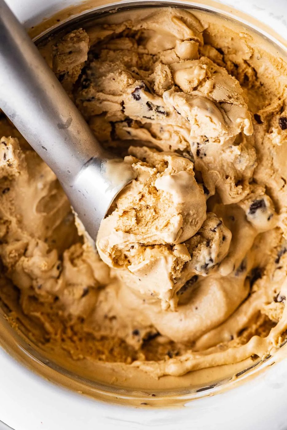 Ice cream sccop in a container of dulce de leche ice cream with chocolate covered pretzels | © Sovuh