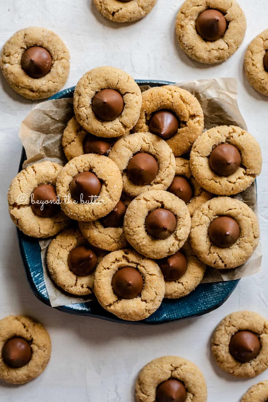 Overhead image of familiar peanut butter blossoms on a parchment lined blue dessert platter | All Images © Sovuh