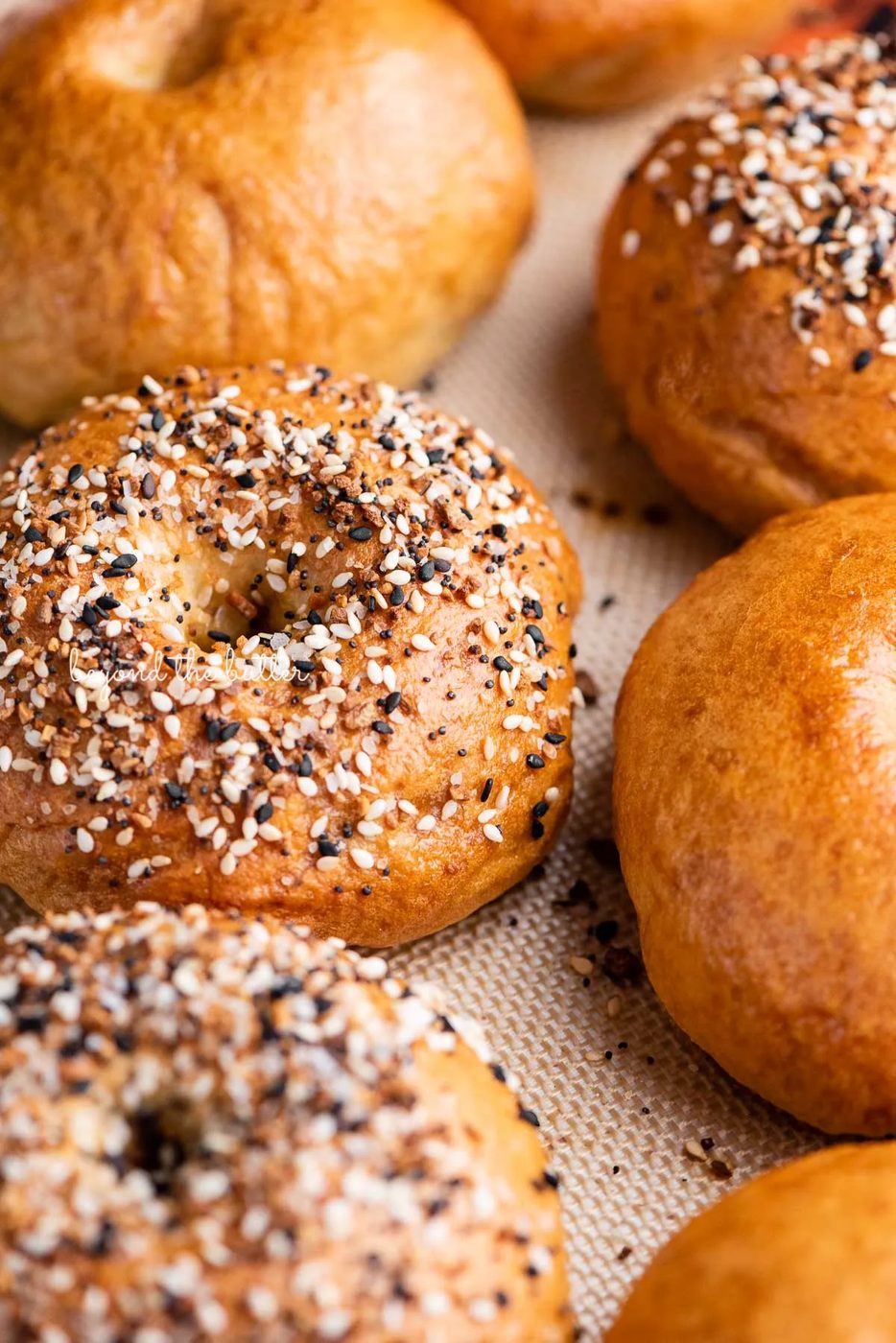 Silicone mat lined baking sheet with just baked house-made bagels | © Sovuh