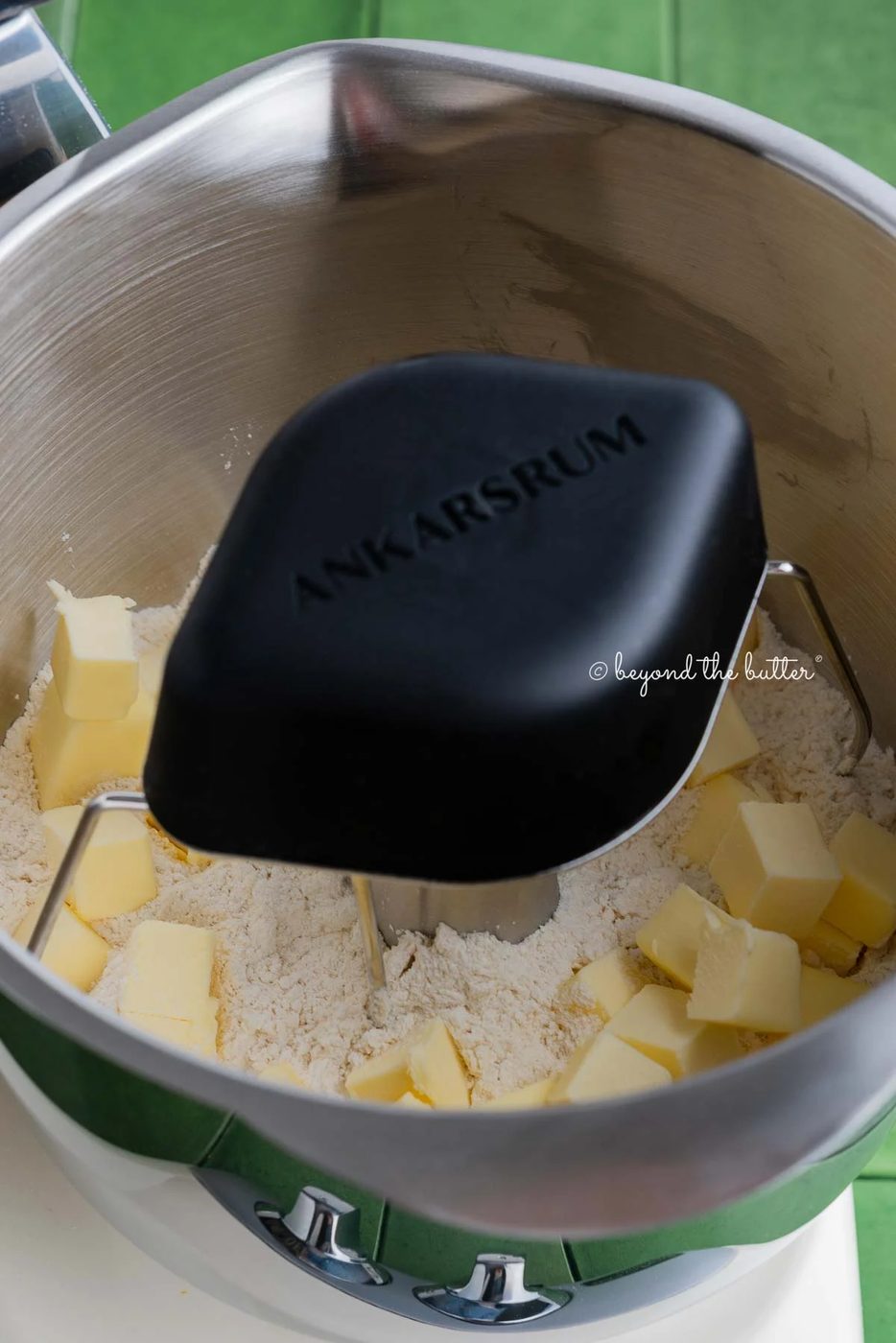 Ankarsrum stainless steel beater bowl with new premium beater set attachment mixing pie crust mixture and cold cubed butter together.