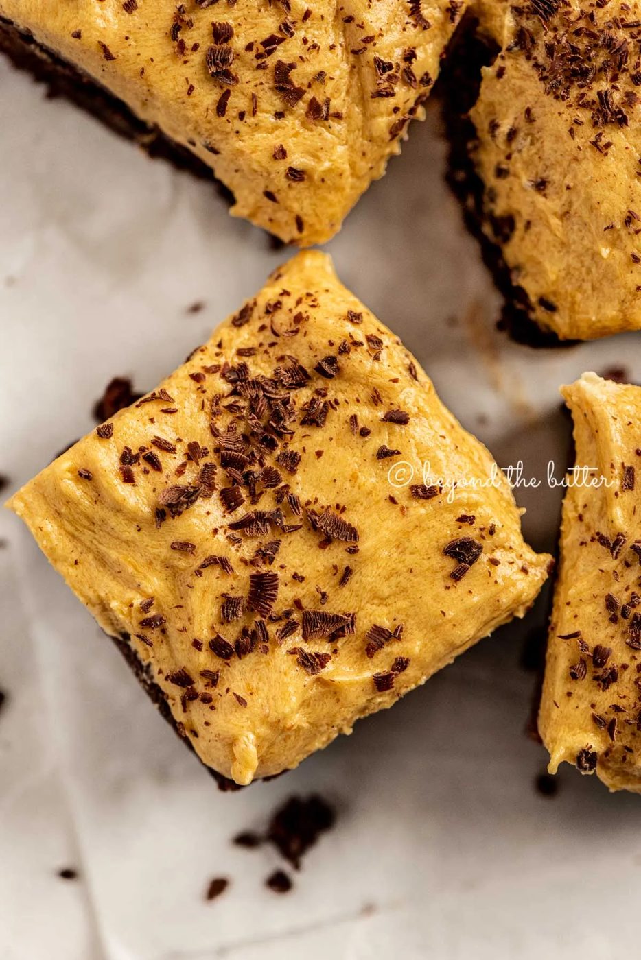 closeup of fudgy chocolate brownies frosted with pumpkin buttercream and topped with chocolate shavings | All Images © Sovuh