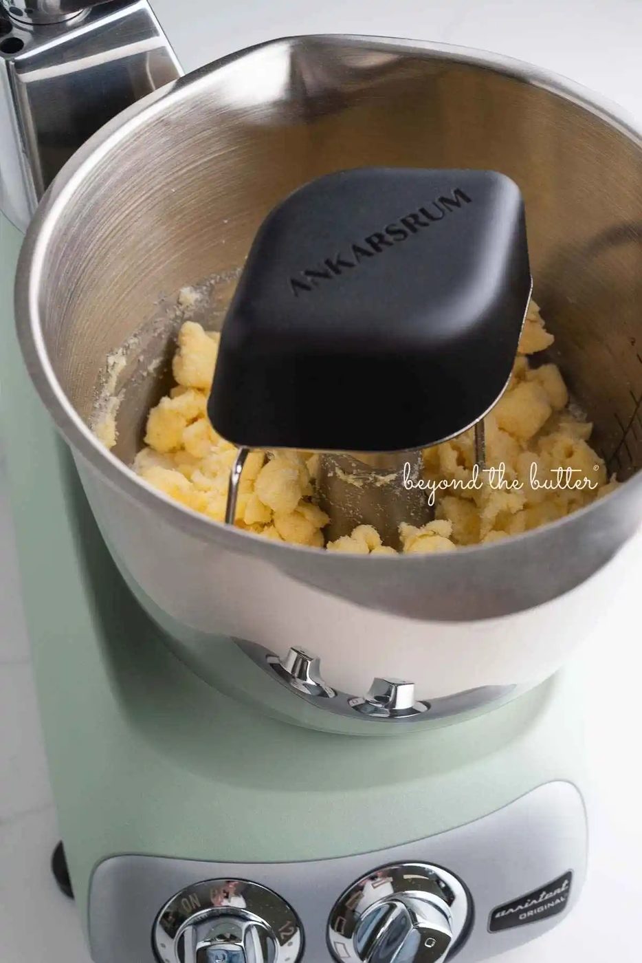 Ankarsrum assistent original mixer in nordic sage mixing butter and sugar together using the premium beater set and cookie whisks.