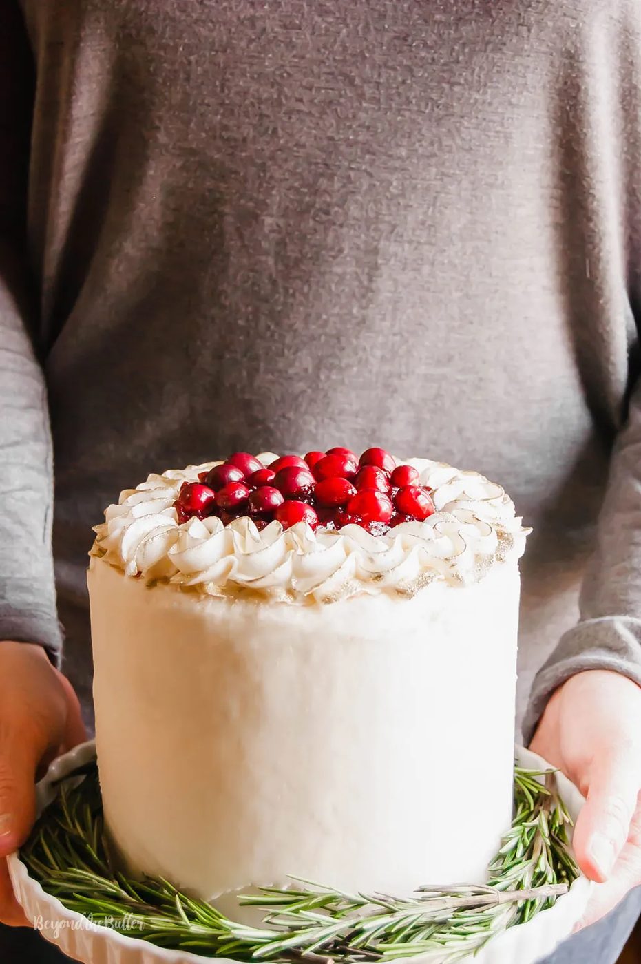 Gingerbread Cake | Person holding Gingerbread Cake with Maple Buttercream Frosting and Cranberry Compote on a cake stand | Image Credit: Sovuh, LLC