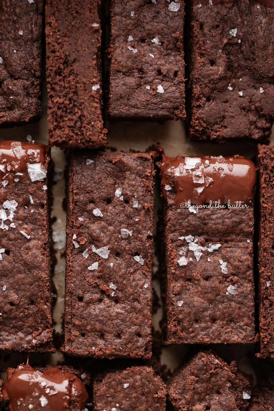 Sliced house-made chocolate shortbread sprinkled with flaky sea salt on natural parchment paper.