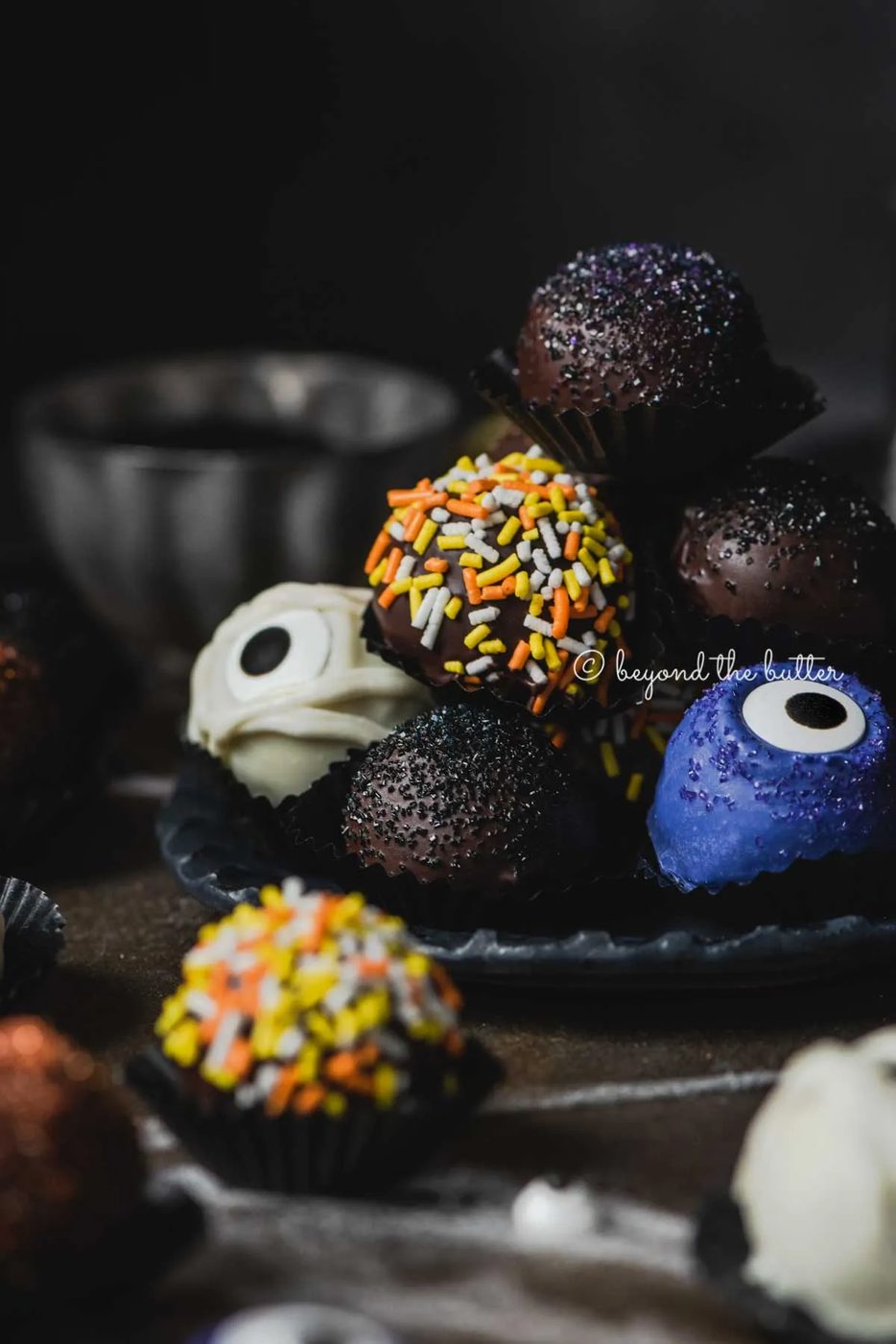 Plate of stacked house-made chocolate truffles with more around it on dark background | All Images © Sovuh