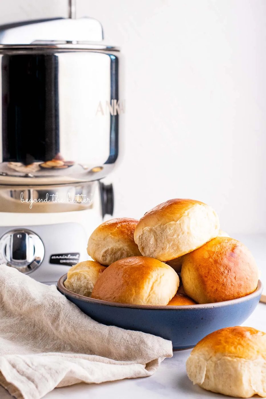 Honey butter dinner rolls in a blue ceramic bowl made with the Ankarsrum Original Mixer | © Sovuh