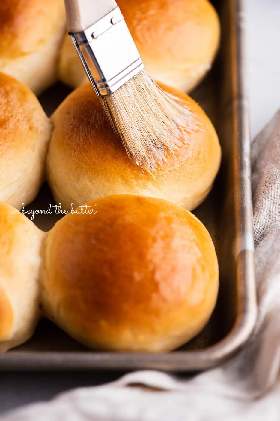Small tray of honey butter dinner rolls being brushed with more honey butter | © Sovuh