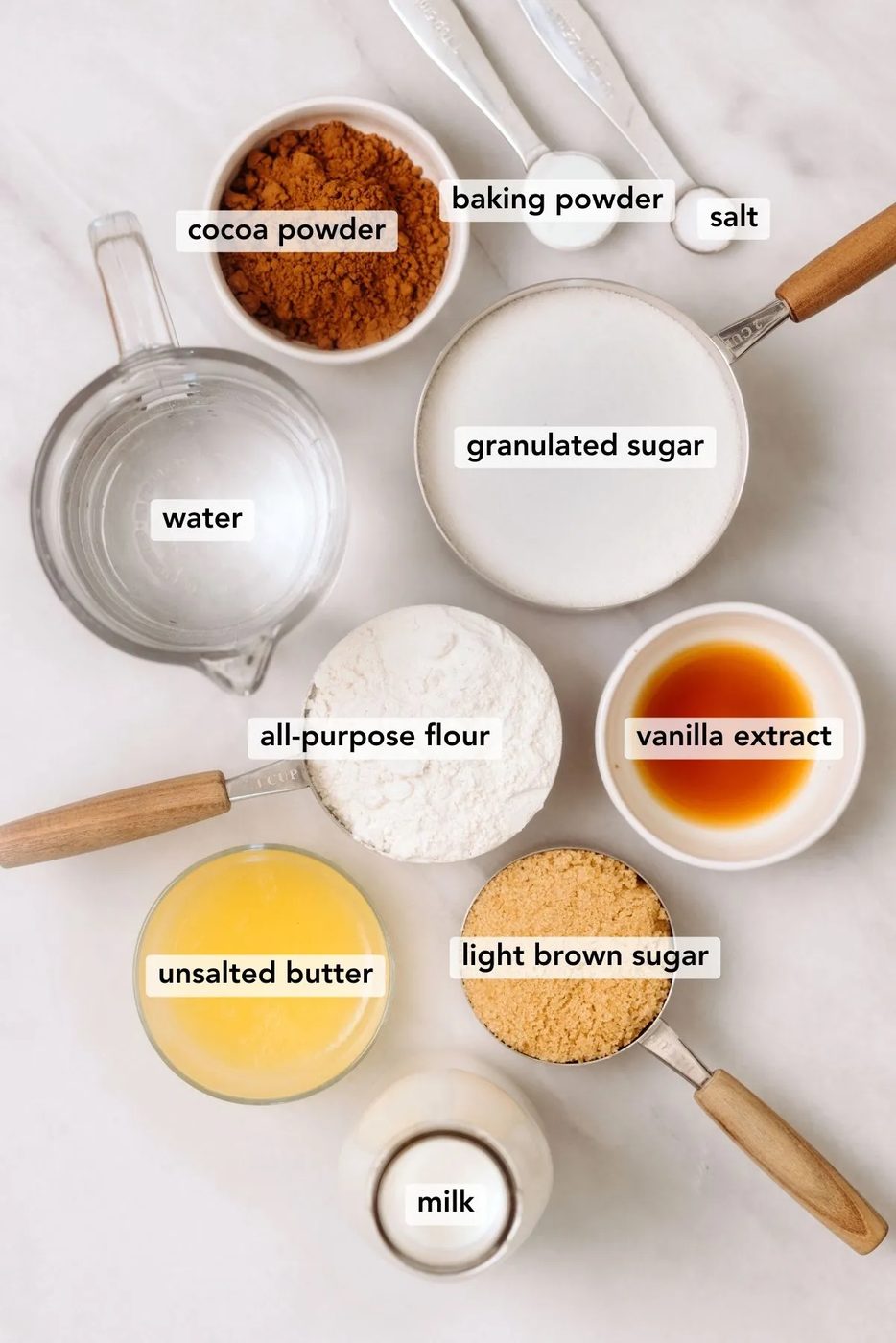 Ingredients needed to make hot fudge chocolate pudding cake displayed on a white marbled background.