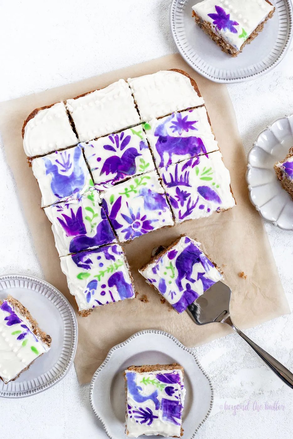 Hummingbird Sheet Cake with White Chocolate Cream Cheese Frosting | Overhead photo of Hummingbird Sheet Cake that's topped with a white chocolate frosting, and stenciled using purple and green frosting | Image and Copyright Policy: © Sovuh, LLC.