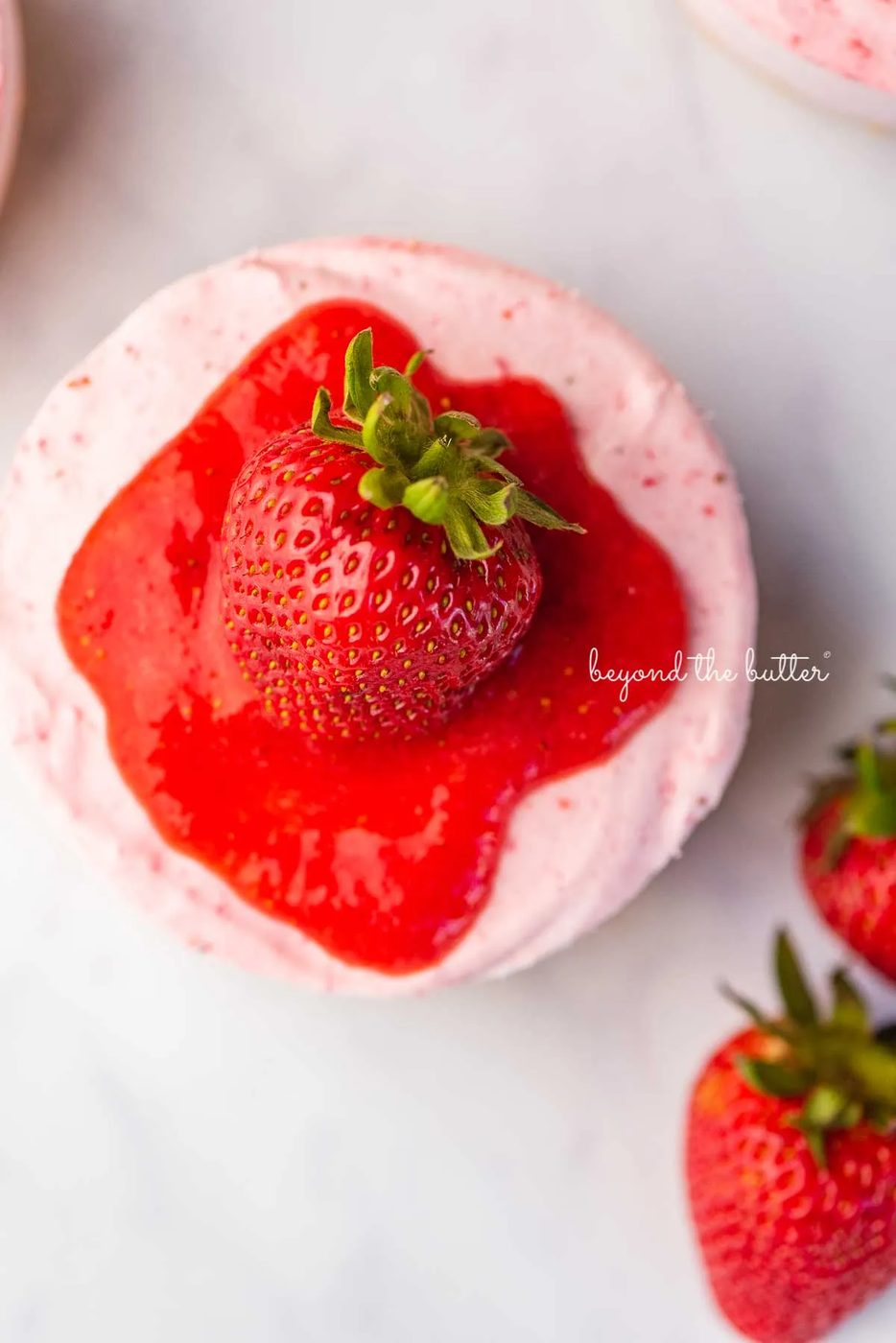 Sliced small 4-inch no-bake strawberry cheesecake on a marbled background | © Sovuh