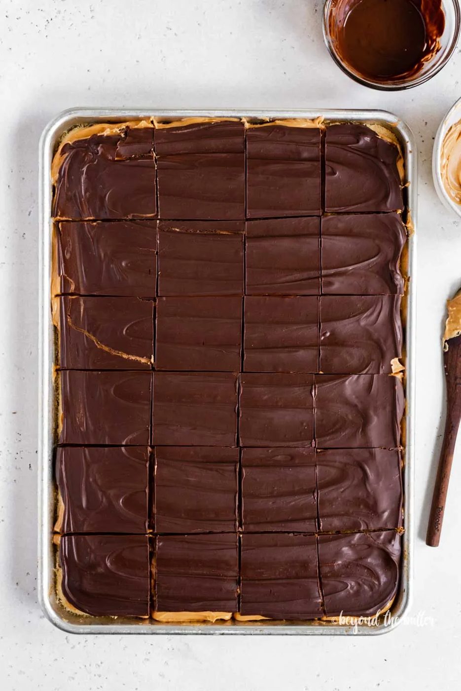 Overhead image of cut peanut butter kandy kakes with bowls of chocolate and peanut butter next to the tray | All Images © Sovuh