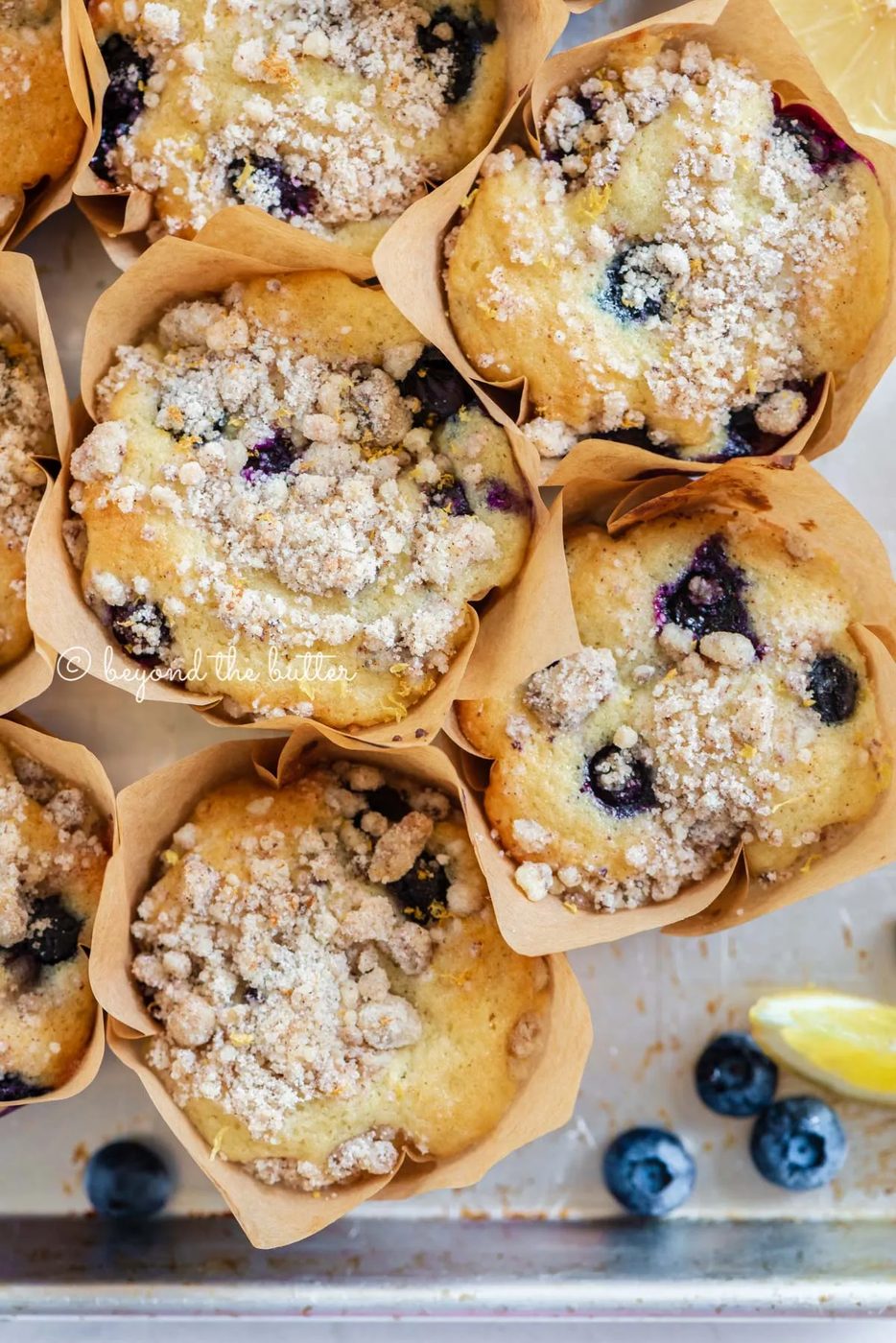 Baking tray filled with bakery style lemon blueberry muffins garnished with slices of lemons and blueberries | All images © Sovuh