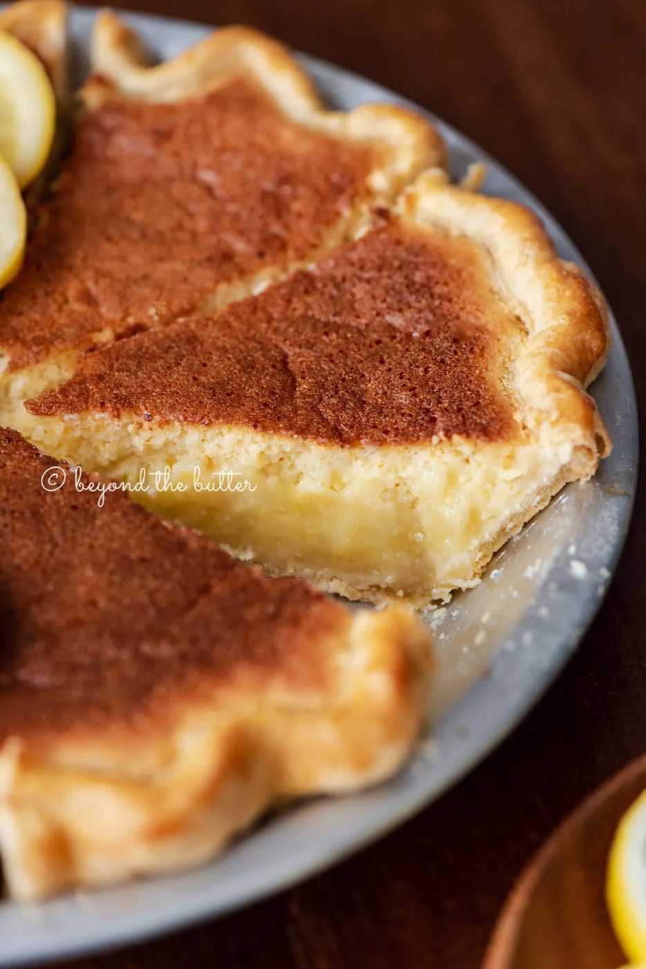 Lemon sponge pie with cut slices on dark wood background with hot lemon tea, and small plate of sliced lemons | All images © Sovuh