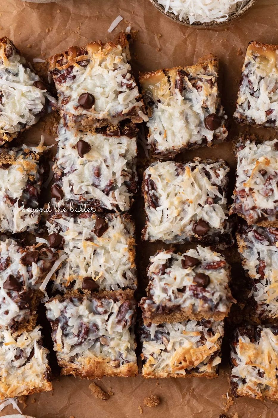 7 layer magic cookie bars on brown parchment paper | © Sovuh