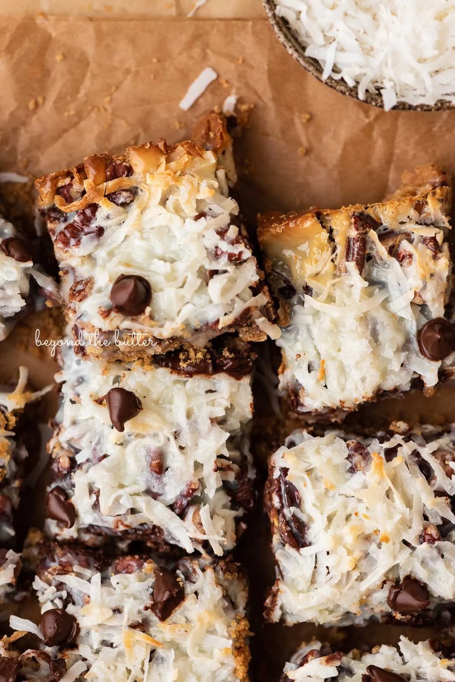 7 layer magic cookie bars on brown parchment paper | © Sovuh