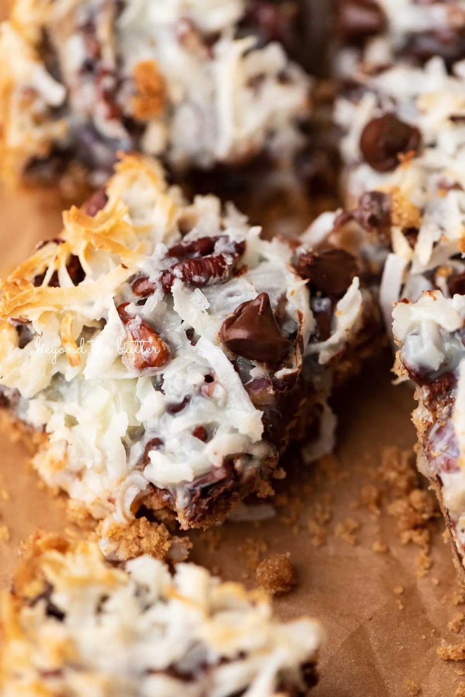7 layer magic cookie bars on brown parchment paper | © Sovuh