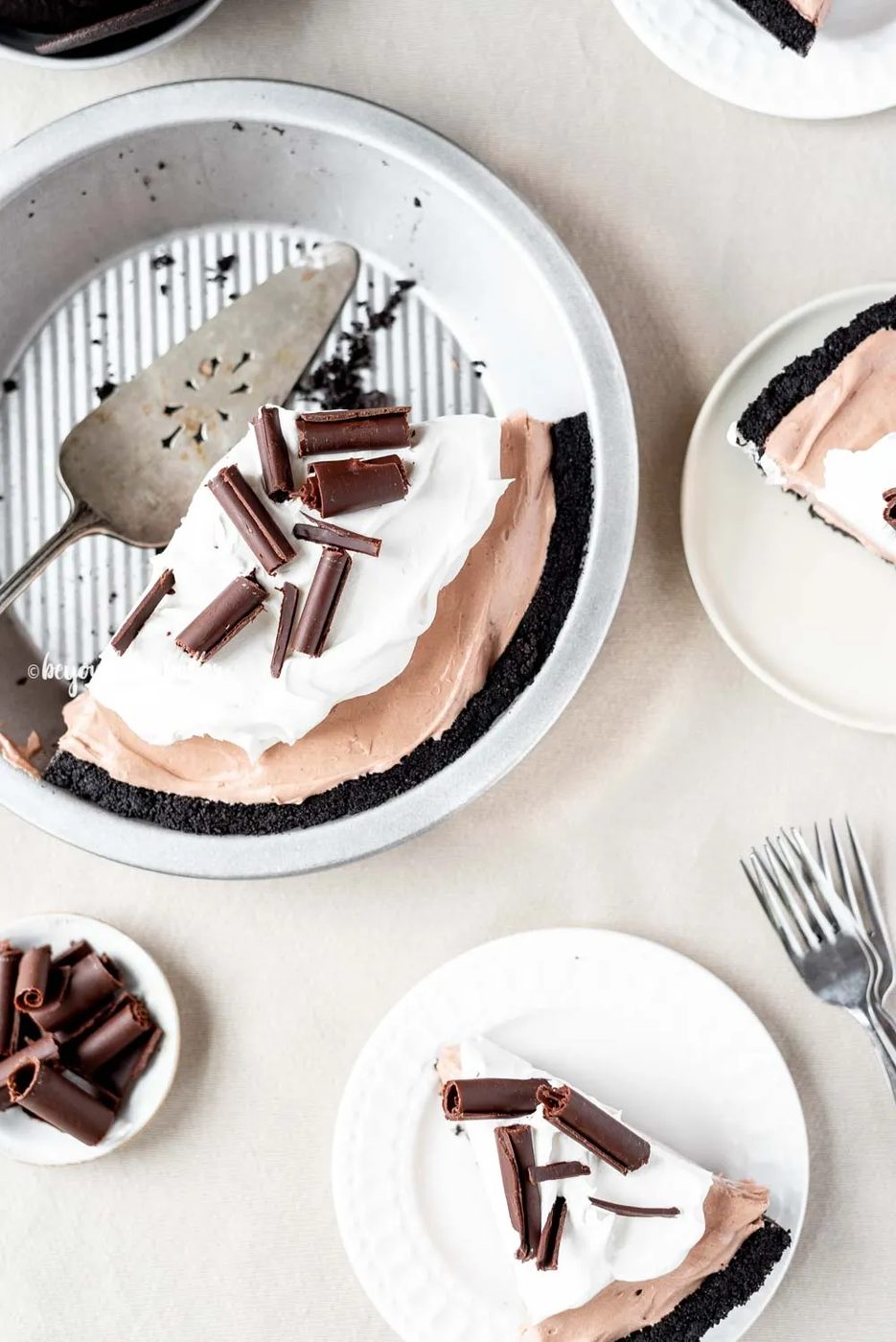 Overhead image of sliced no-bake chocolate cream pie with slices of pie on dessert plates next to it | All Images © Sovuh