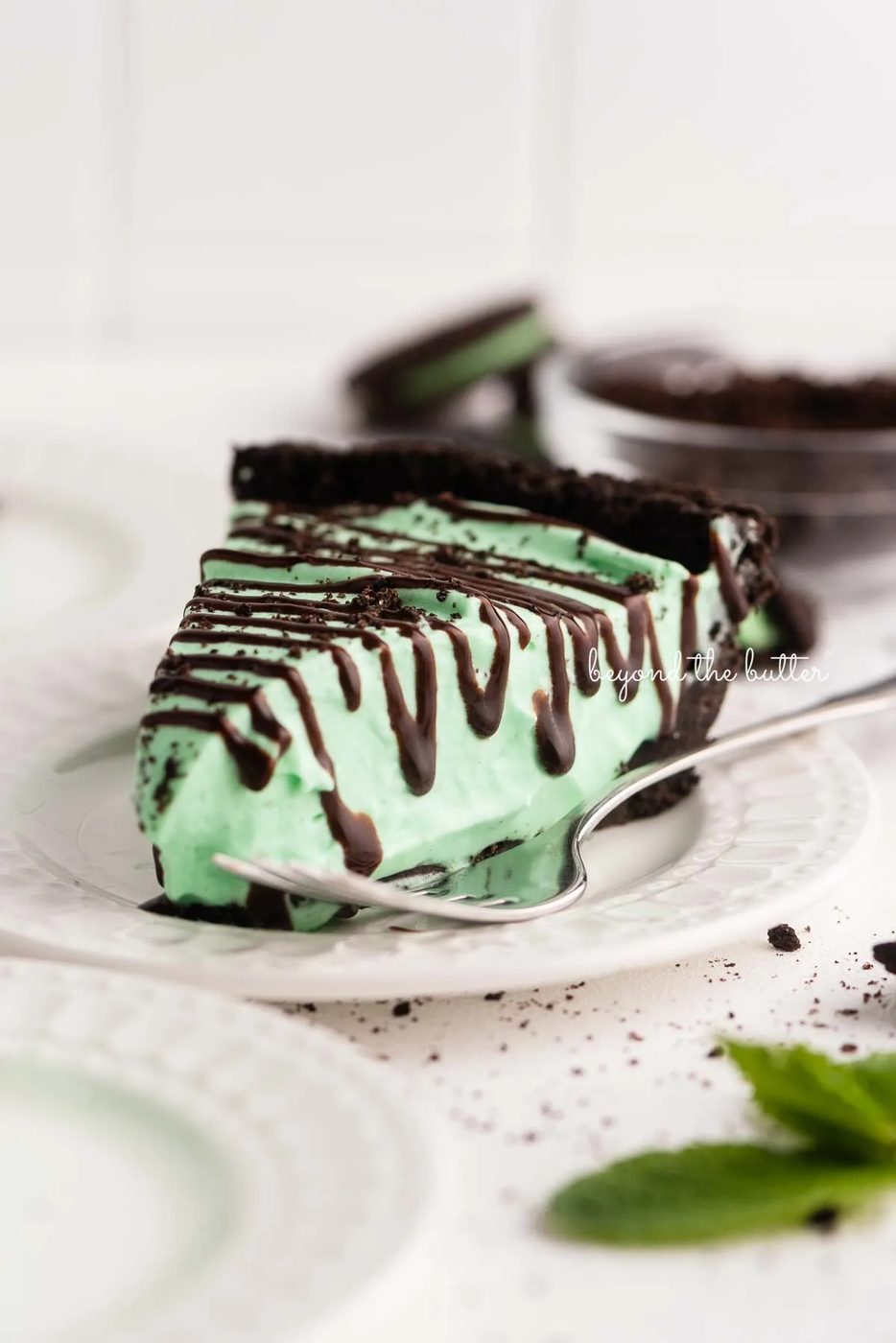 Dessert plates with slices of no bake mint chocolate pie with chocolate syrup drizzled over the top | © Sovuh