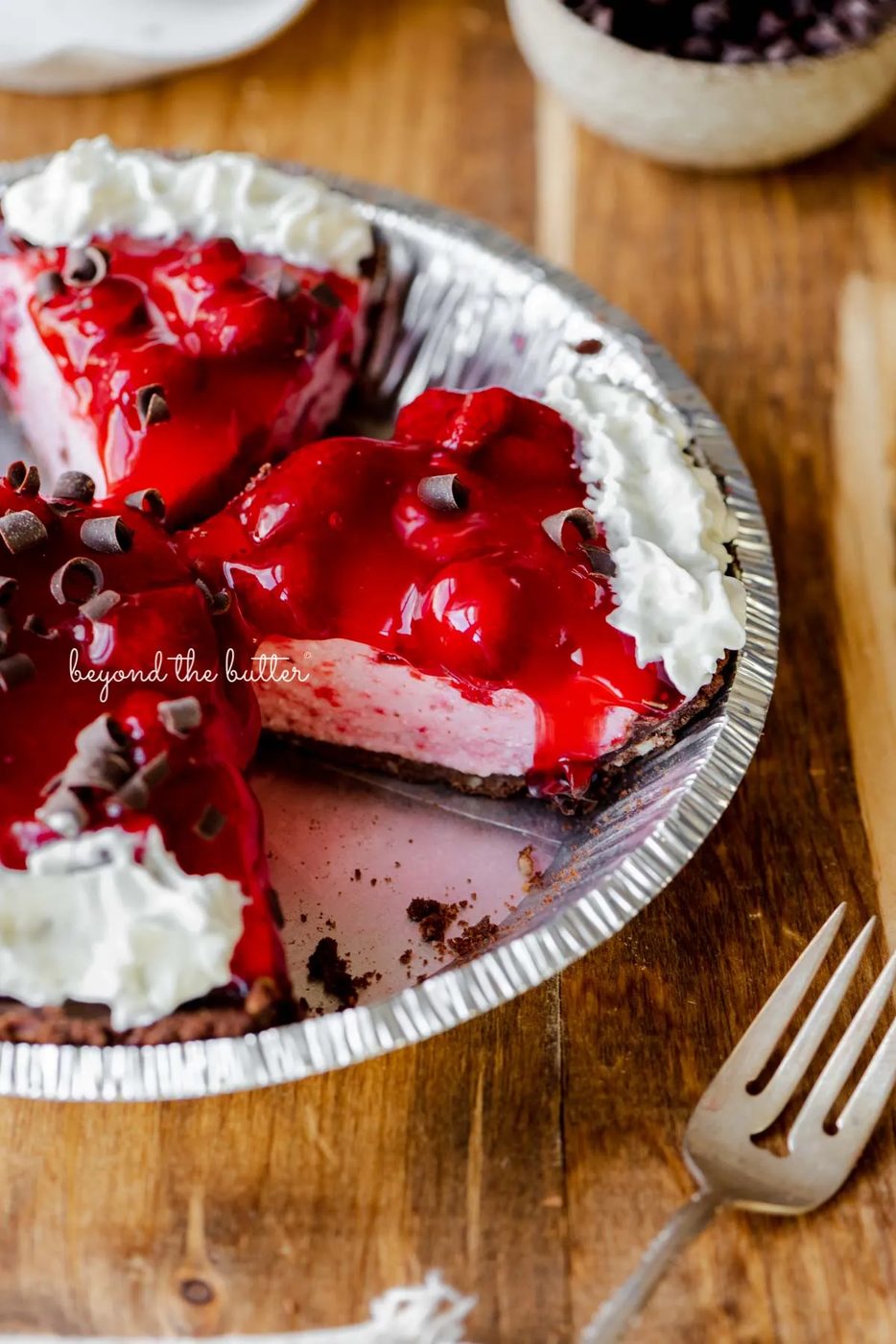Sliced no bake strawberry chocolate cream pie on wood table with a fork and small bowl of chocolate curls nearby | All images © Sovuh