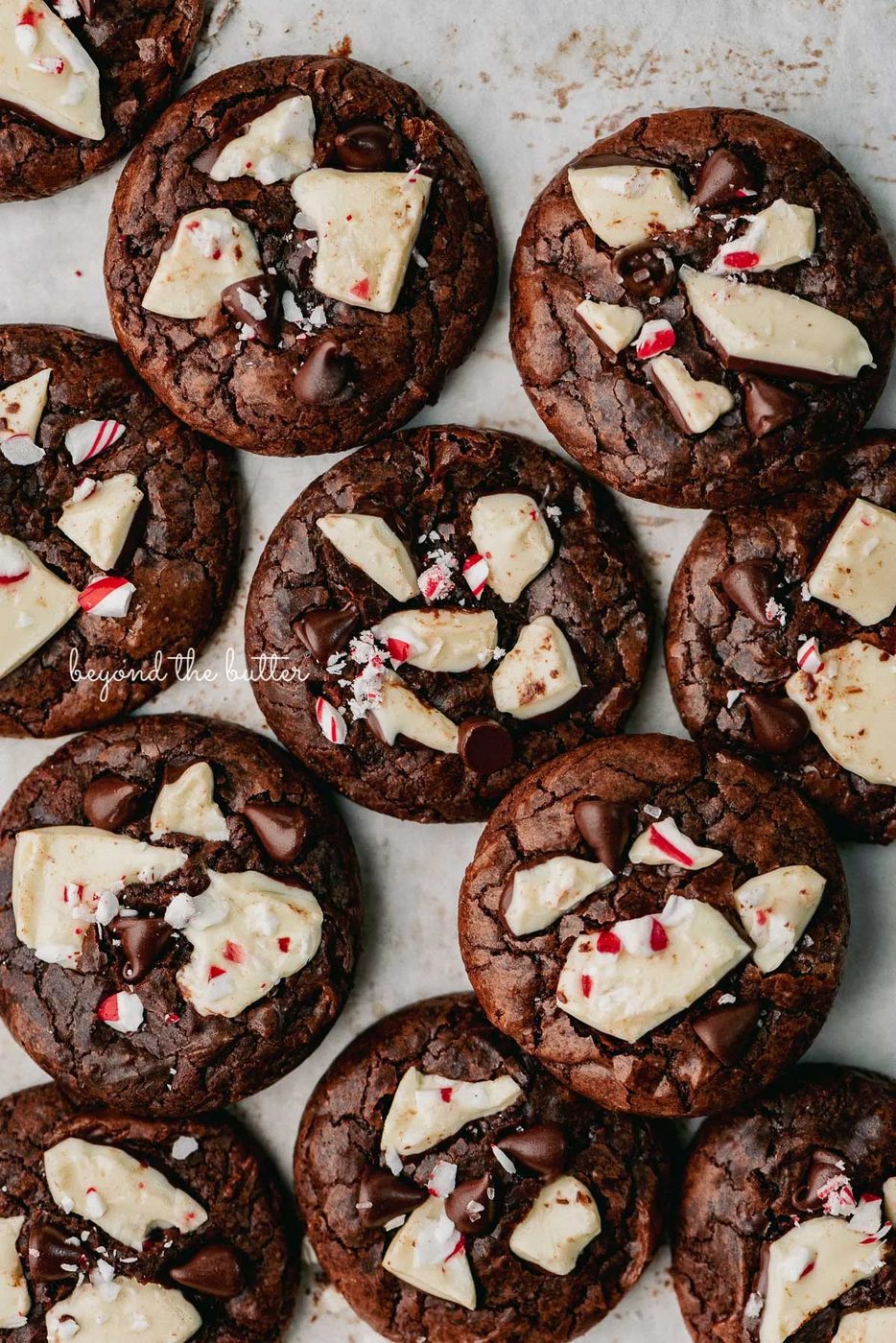 Just baked peppermint bark brownie crinkle cookies on a parchment paper lined baking sheet | © Beyond the Buter